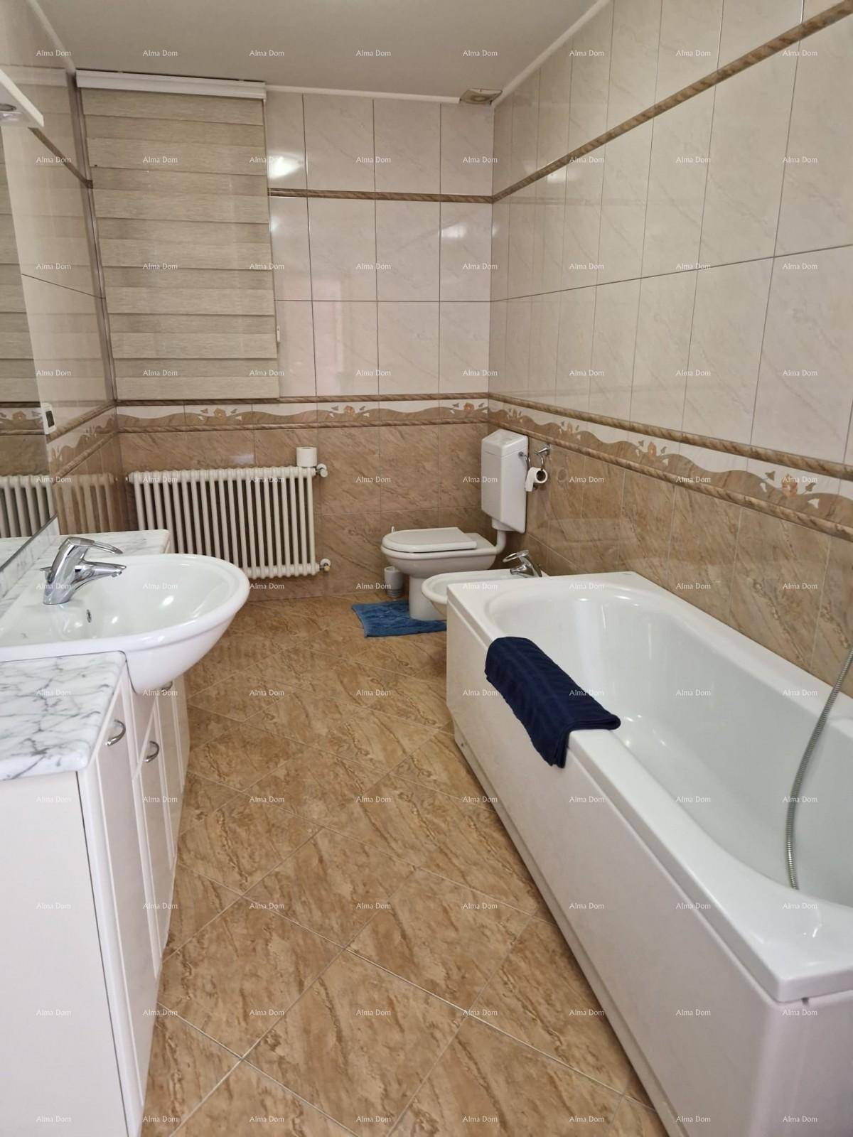 Badezimmer mit Badewanne, Waschbecken, WC und Fliesen an Wänden und Boden.