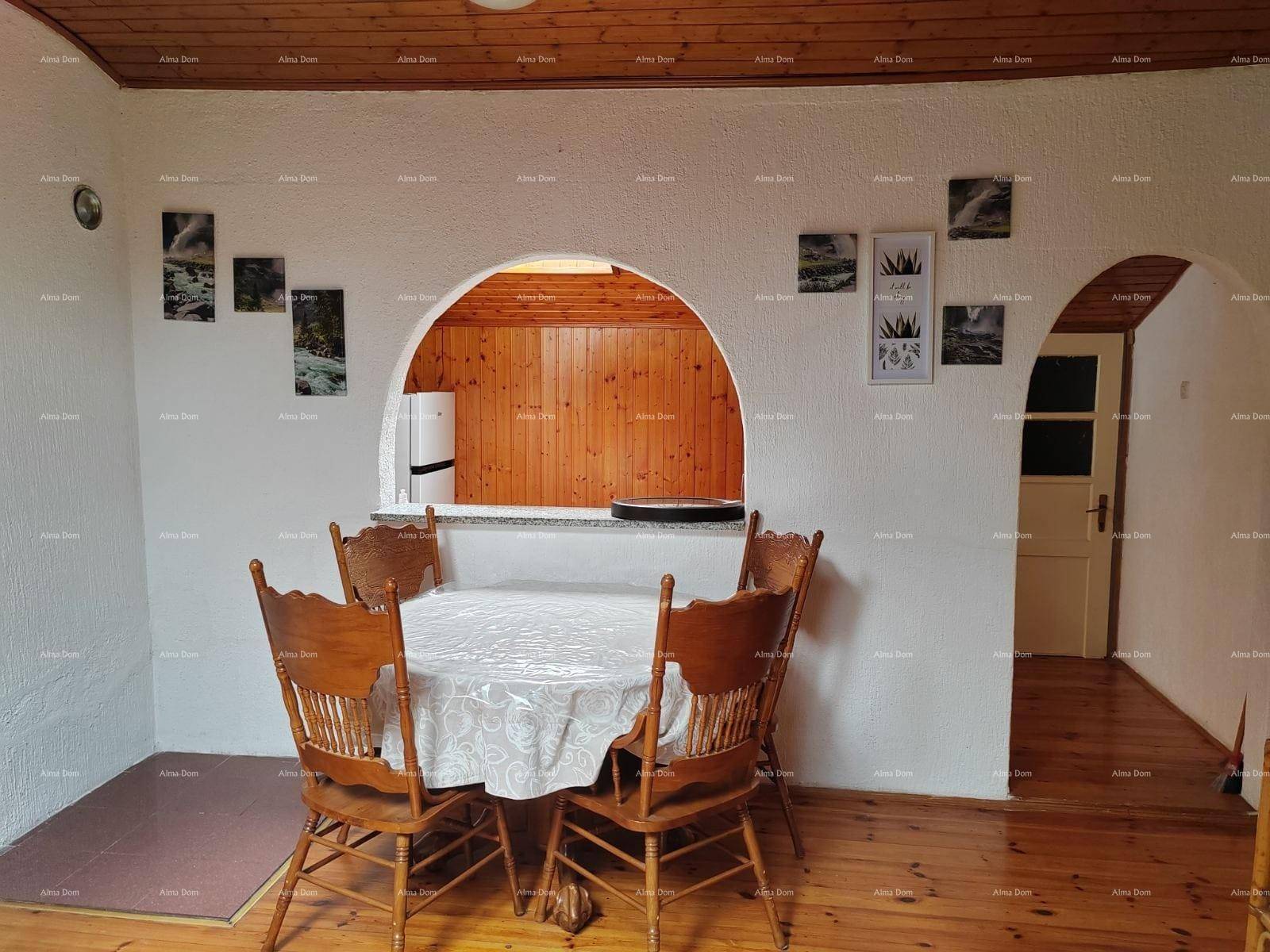 Essbereich mit Holzboden und traditionellen Holzstühlen, durch einen Bogen zur Küche hin offen.