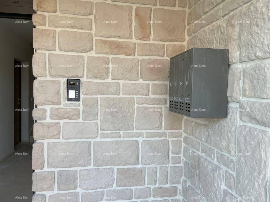 Außenwand mit Natursteinverkleidung, Gegensprechanlage und Briefkästen am Eingangsbereich.