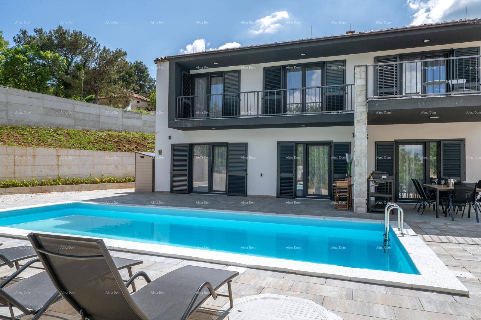 Ansicht des modernen Hauses mit großem Pool und Liegestühlen unter strahlend blauem Himmel.