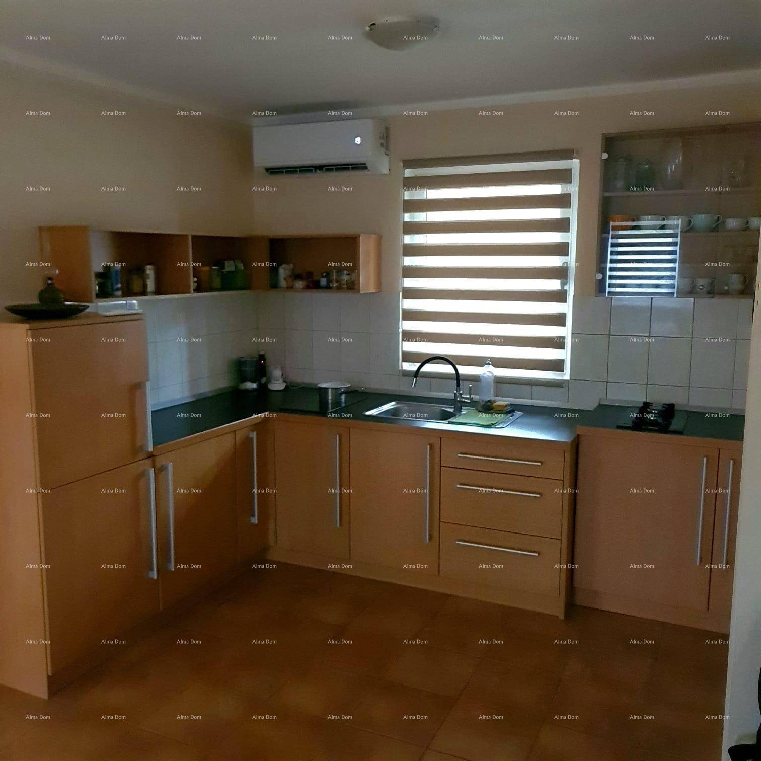 Funktionale Küche mit Holzschränken, dunkler Arbeitsplatte und Fenster mit Jalousien.