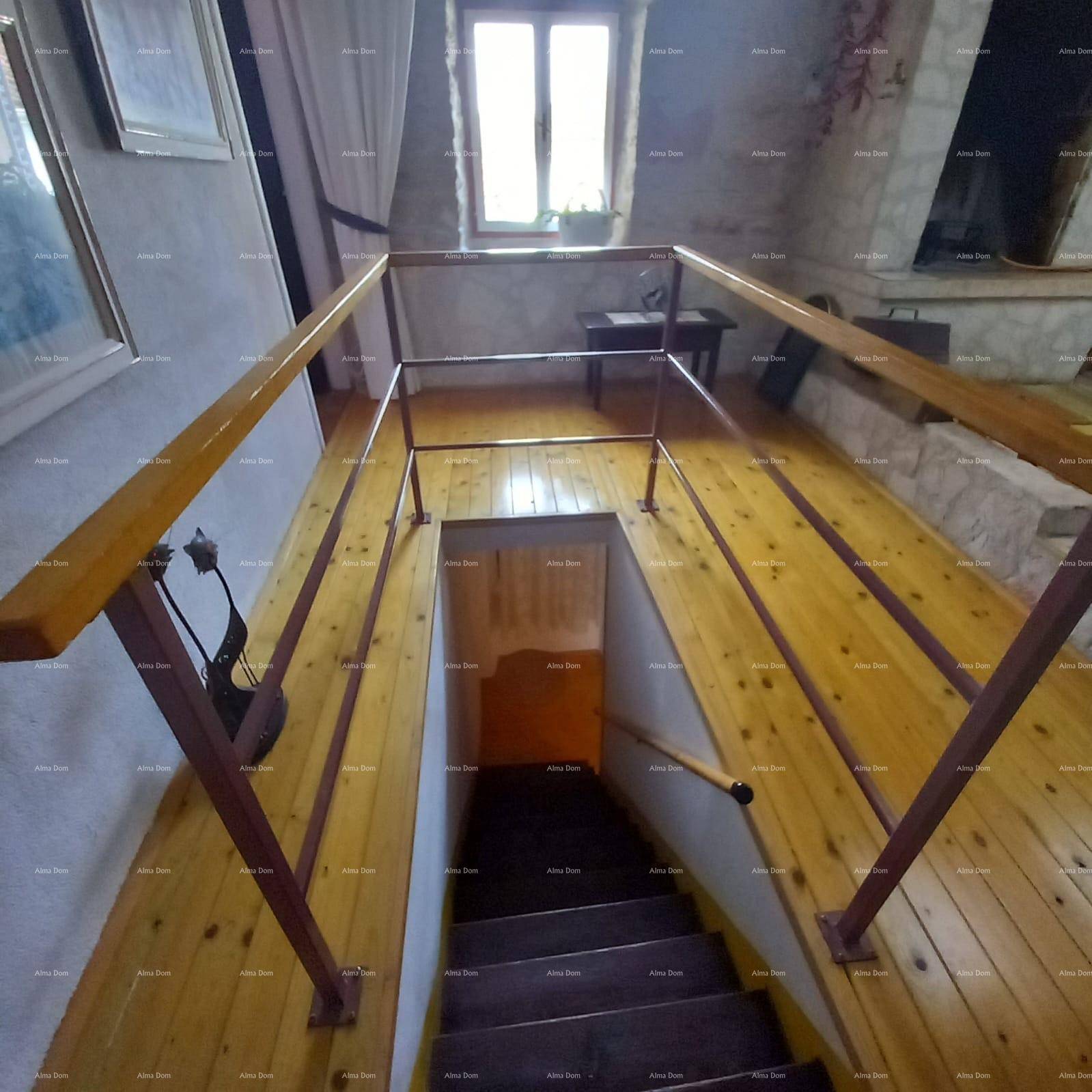 Holztreppe mit Metallgeländer führt in den unteren Bereich, umgeben von Holzböden und natürlichem Licht.