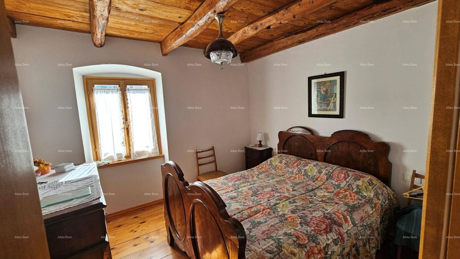 Helles Schlafzimmer mit Holzbalkendecke, Dielenboden und rustikalem Holzfenster.