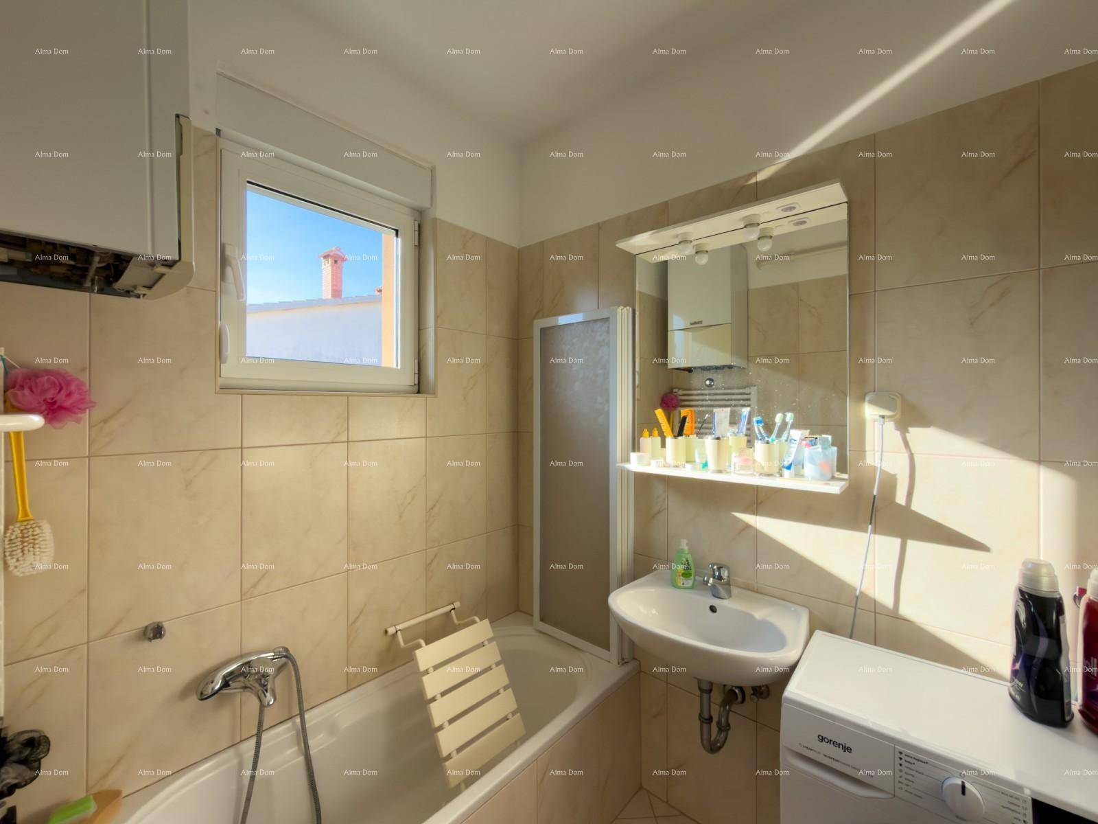 Badezimmer mit Badewanne, Waschbecken, Spiegel und beigefarbenen Fliesen.