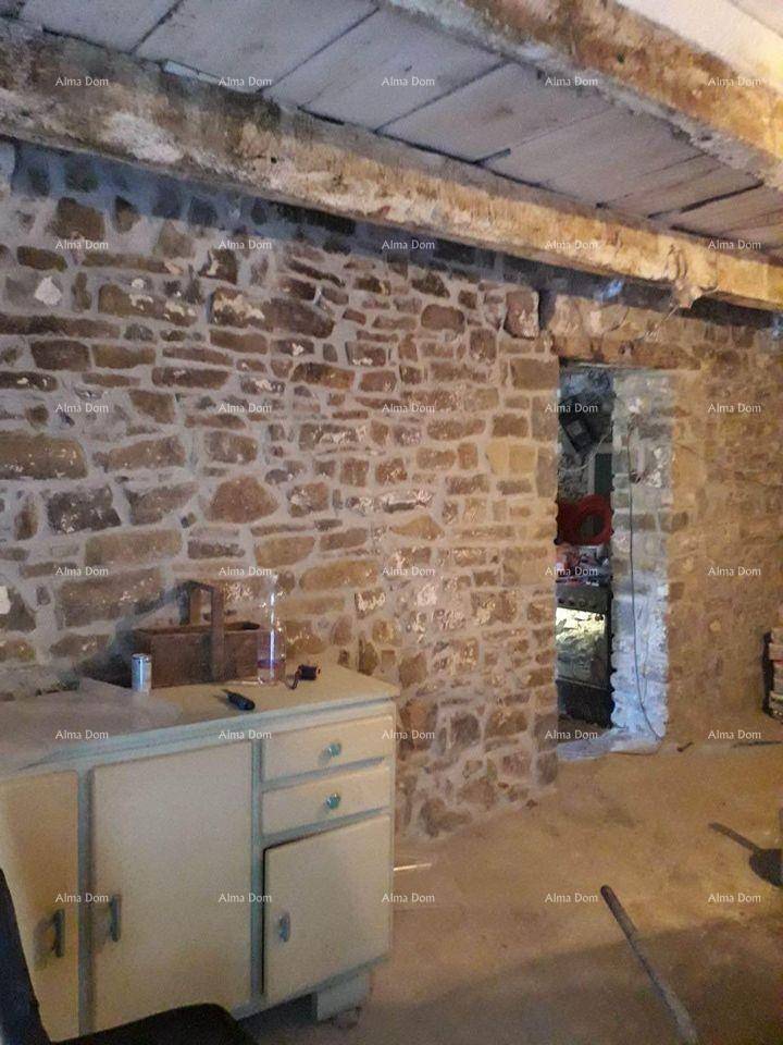 Innenraum mit freiliegenden Steinmauern, Holzbalkendecke und einem alten Schrank.