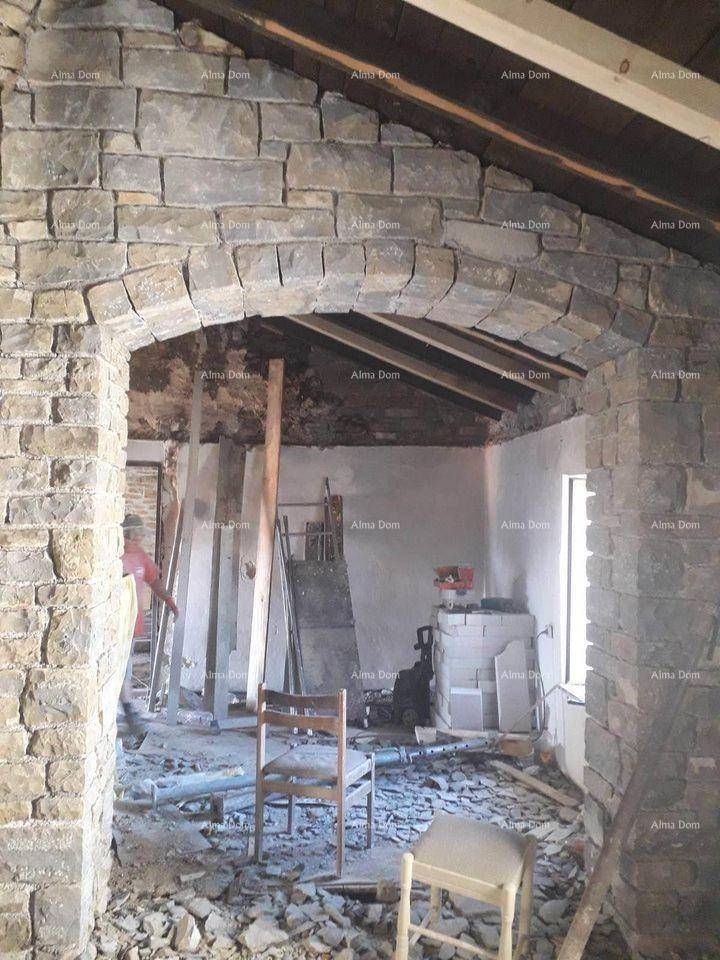 Innenraum im Rohbau mit Steinmauern, freiliegenden Holzbalken und einem Bogen.