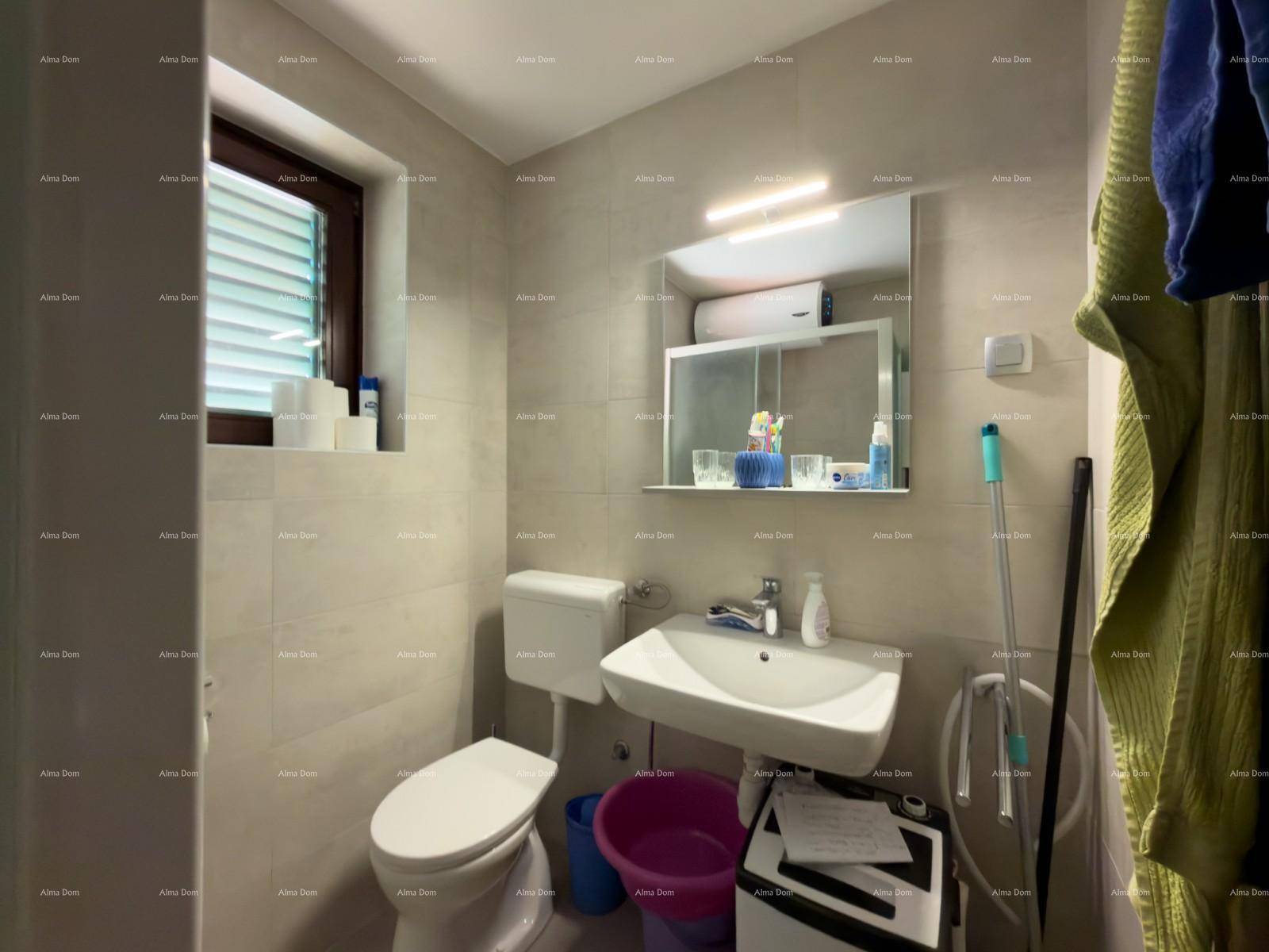 Helles Badezimmer mit Fenster, WC, Waschbecken und Spiegel, ausgestattet mit Fliesenboden.