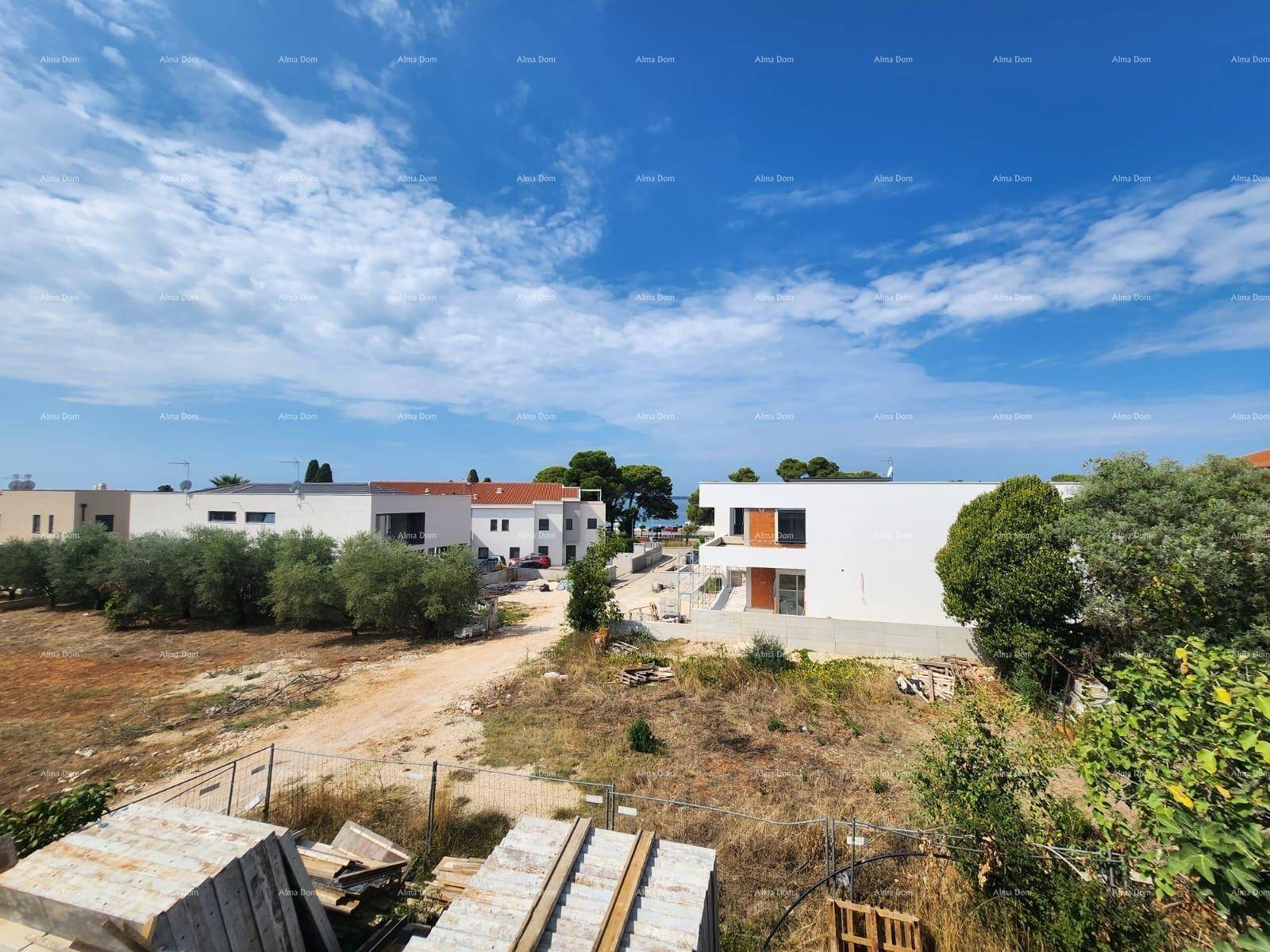 Weitläufige Baustelle mit mehreren im Bau befindlichen Gebäuden und Blick auf das Meer in der Ferne.