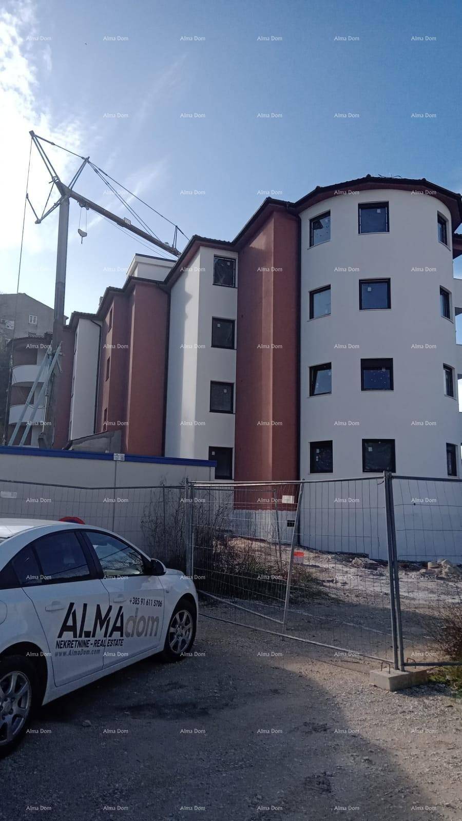 Neubau eines Mehrfamilienhauses mit moderner Fassade und Baustellenkran im Hintergrund.