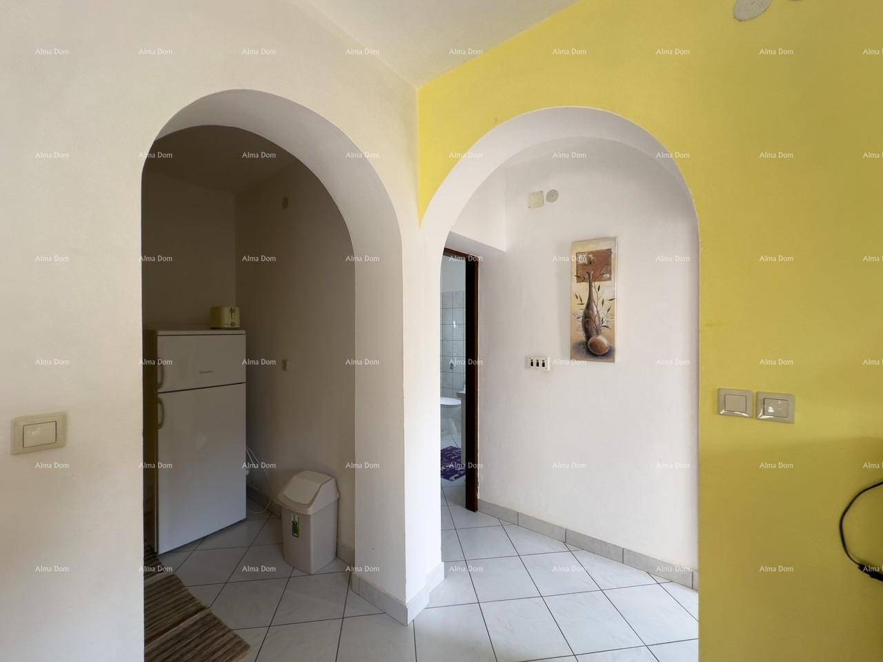 Durchgangsbereich mit zwei Bögen, der zu einer kleinen Nische mit Kühlschrank und einem Badezimmer führt.