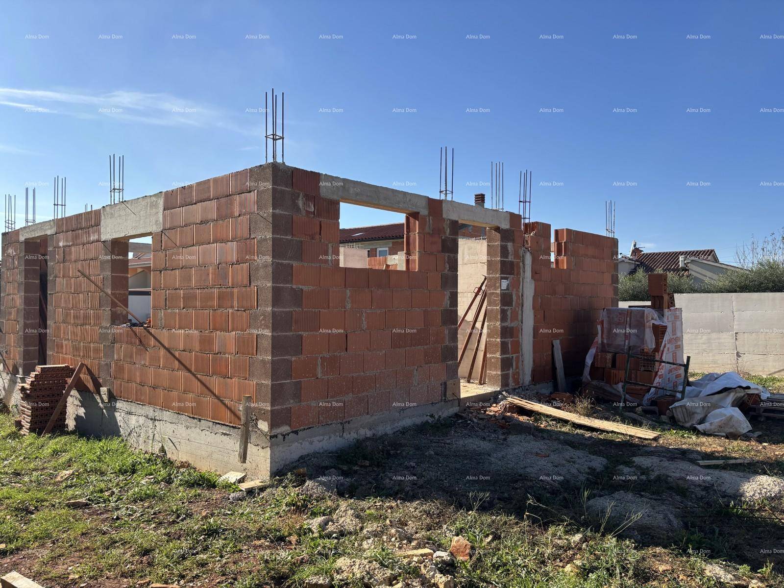 Baustelle eines Hauses mit Rohbau aus Ziegeln und vorbereiteten Fensteröffnungen.