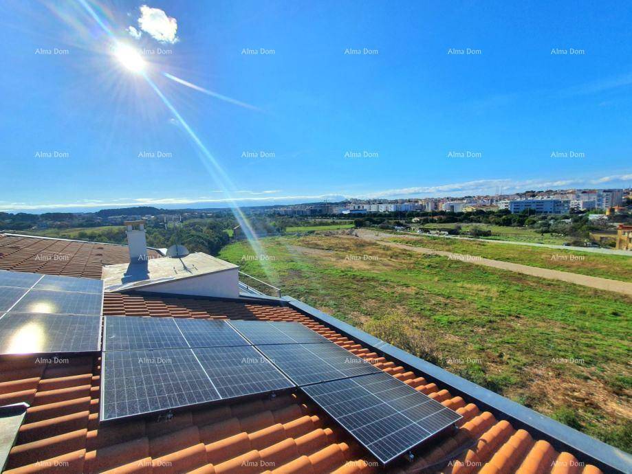 Dach mit Solarmodulen und weitem Blick über die Landschaft unter blauem Himmel.