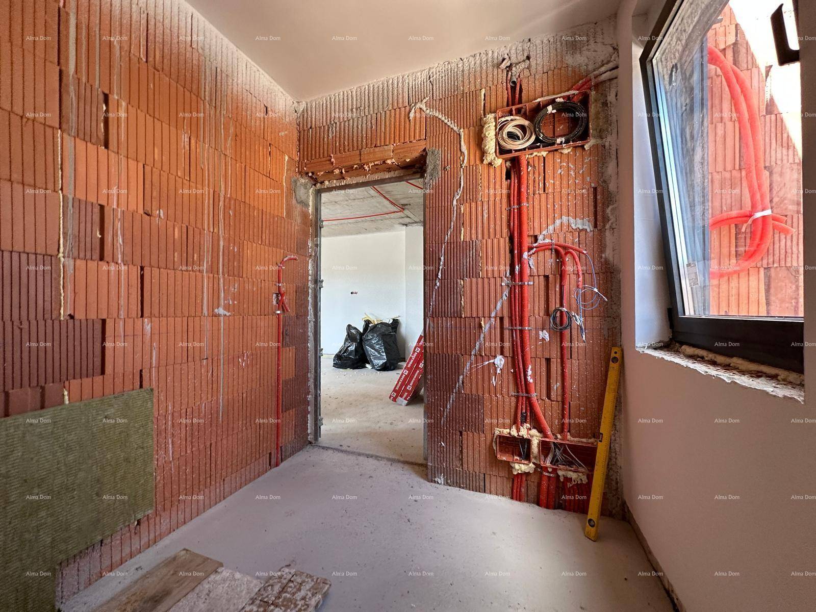 Raum im Rohbau mit unverputzten Ziegelwänden, sichtbaren Elektroinstallationen und einem Fenster.