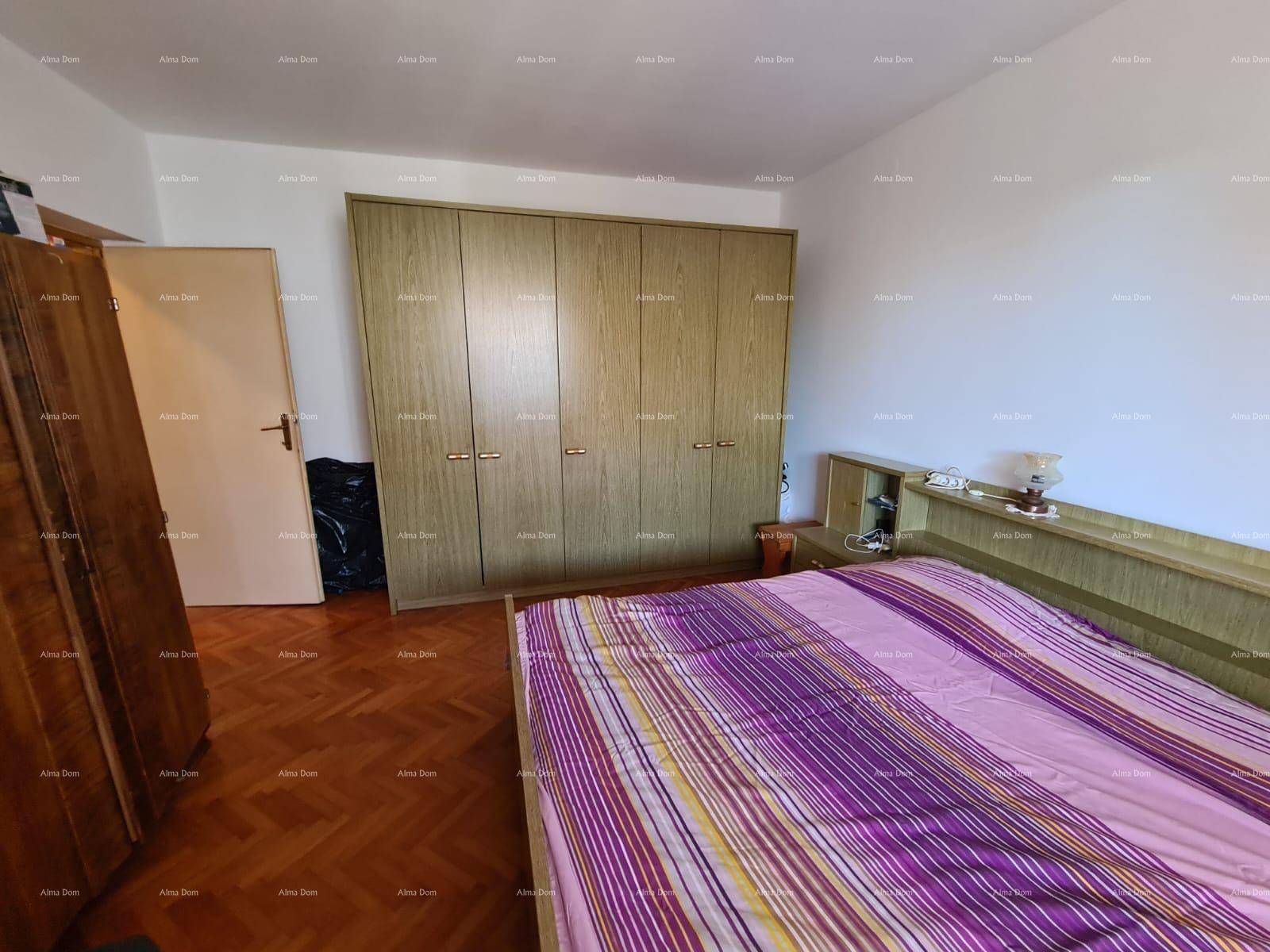 Schlafzimmer mit Doppelbett, Holzparkett und einem großen Kleiderschrank.