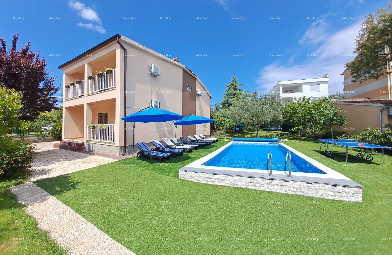 Außenansicht des Hauses mit Balkonen, Poolbereich und großem Garten mit Rasenfläche.