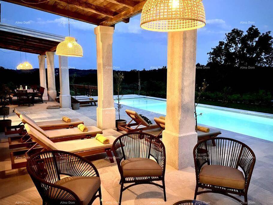 Abendliche Stimmung auf der Terrasse mit beleuchtetem Pool und bequemen Lounge-Möbeln.