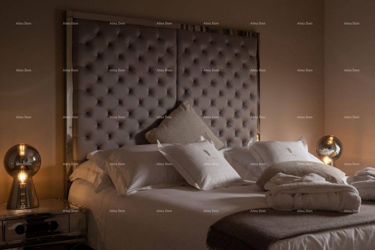 Luxuriöses Schlafzimmer mit einem großen, gesteppten Kopfteil und stimmungsvoller Beleuchtung.