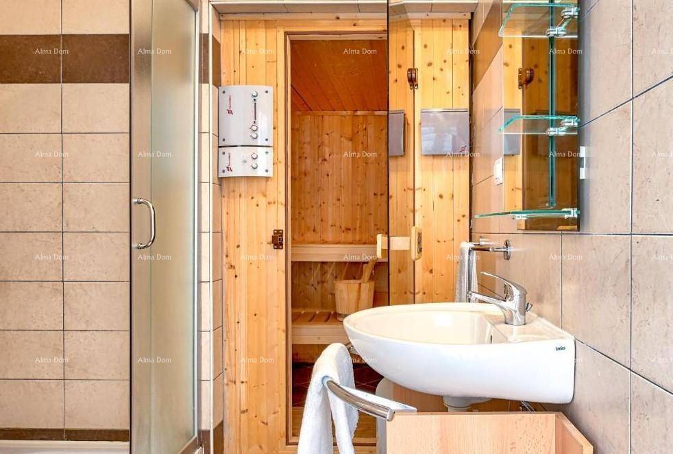 Modernes Badezimmer mit Waschbecken, Dusche und Zugang zur Holzsauna.