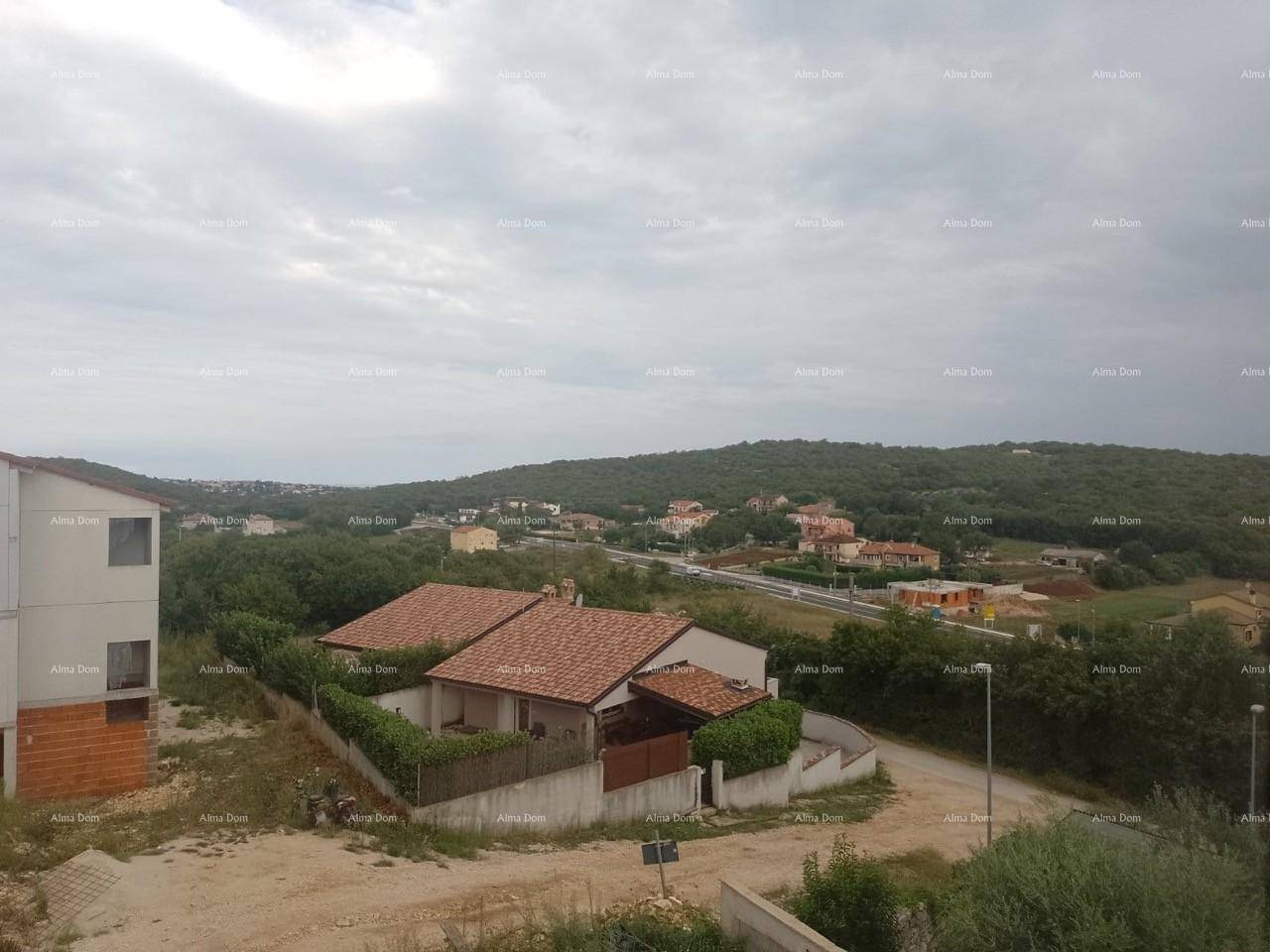 Panoramablick auf die grüne Landschaft mit Wohnhäusern und einer Straße unter bewölktem Himmel.