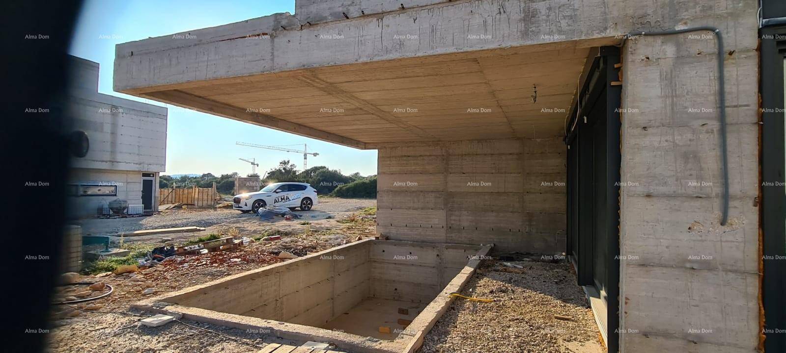 Blick auf den Rohbau und die Baustelle mit einem Fahrzeug und Kran im Hintergrund.