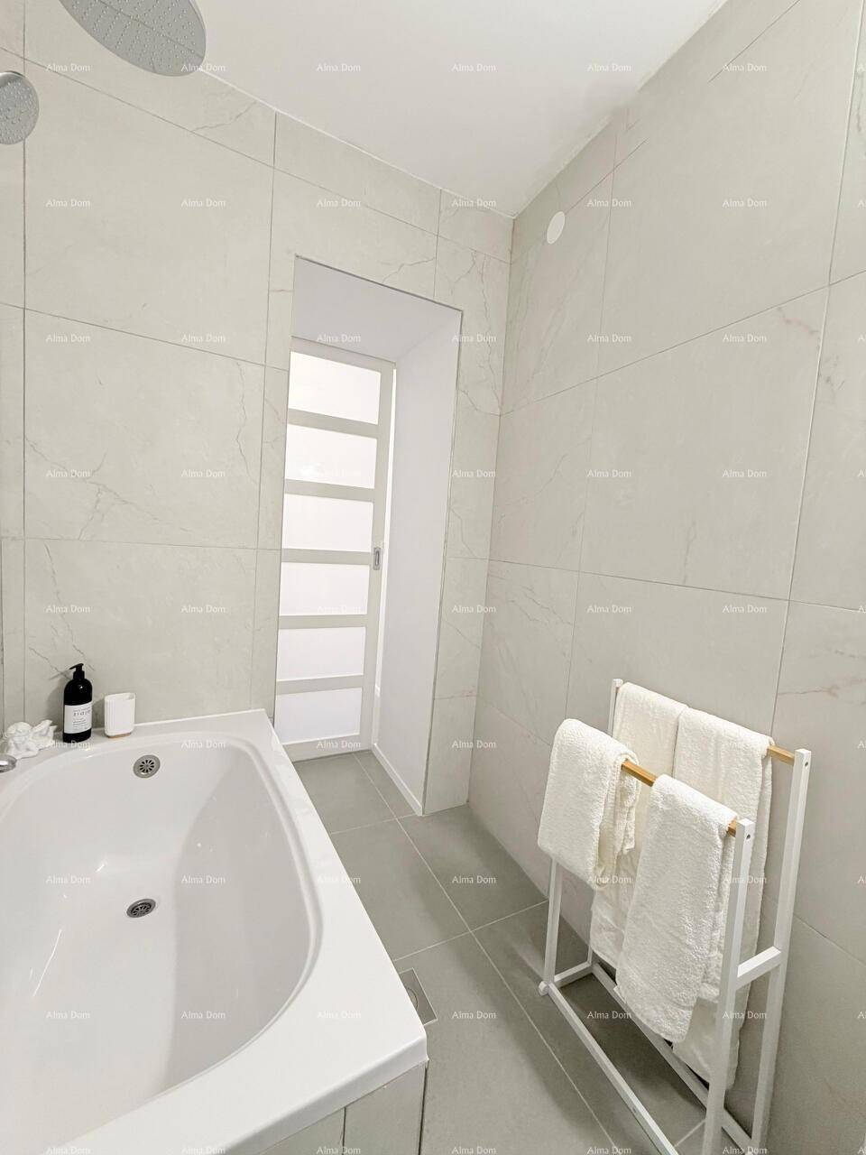 Modernes Badezimmer mit Badewanne, weißen Fliesen und einem Handtuchhalter, sehr sauber.