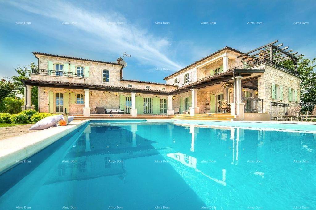 Erfrischender Poolbereich vor der charmanten Steinvilla mit hellgrünen Fensterläden und klarem Himmel.