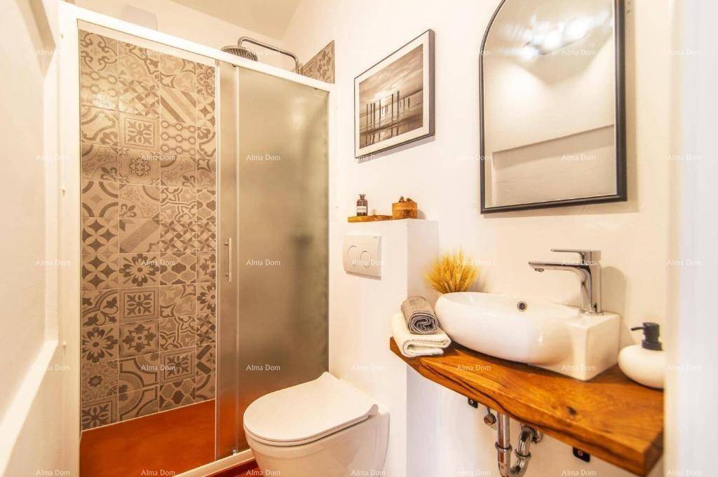 Modernes Badezimmer mit Waschbecken auf Holzplatte, Duschkabine und gemusterten Wandfliesen.