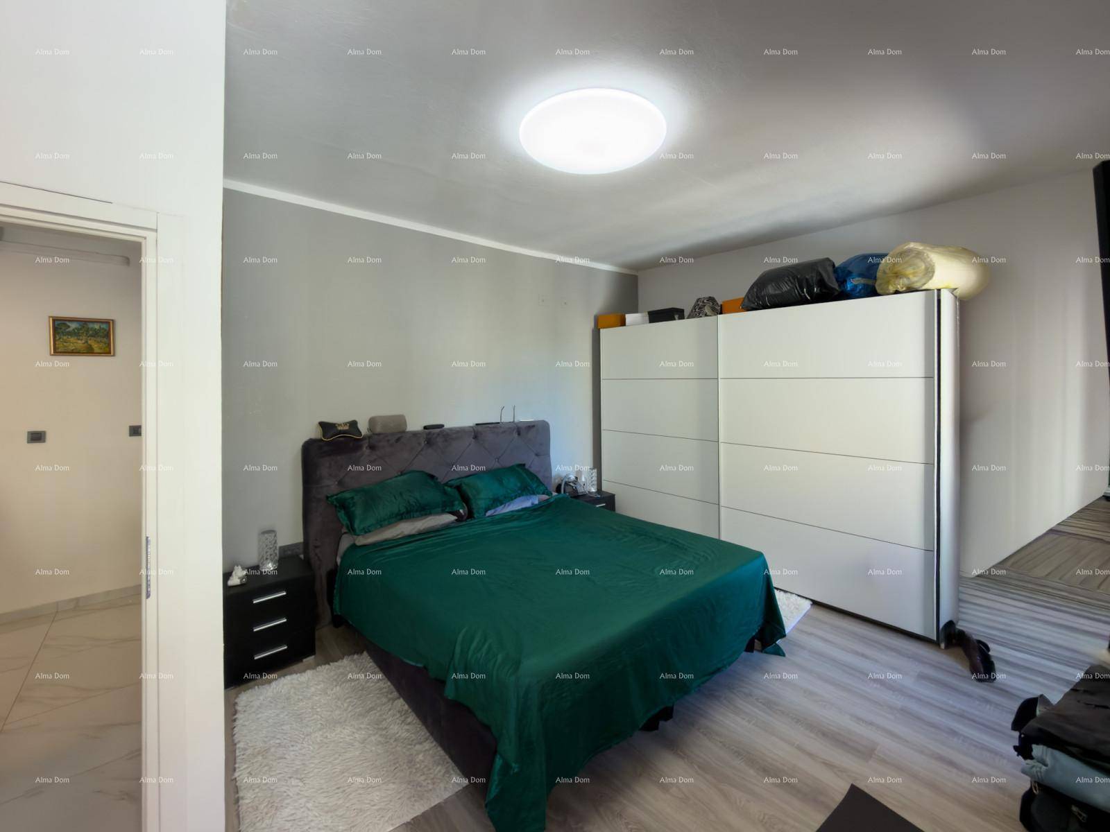 Helles Schlafzimmer mit Doppelbett, Kleiderschrank und moderner Deckenleuchte.