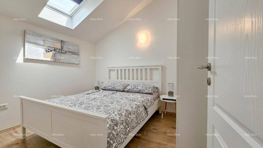 Helles Schlafzimmer im Dachgeschoss mit Holzboden, weißem Bett und Dachfenster.