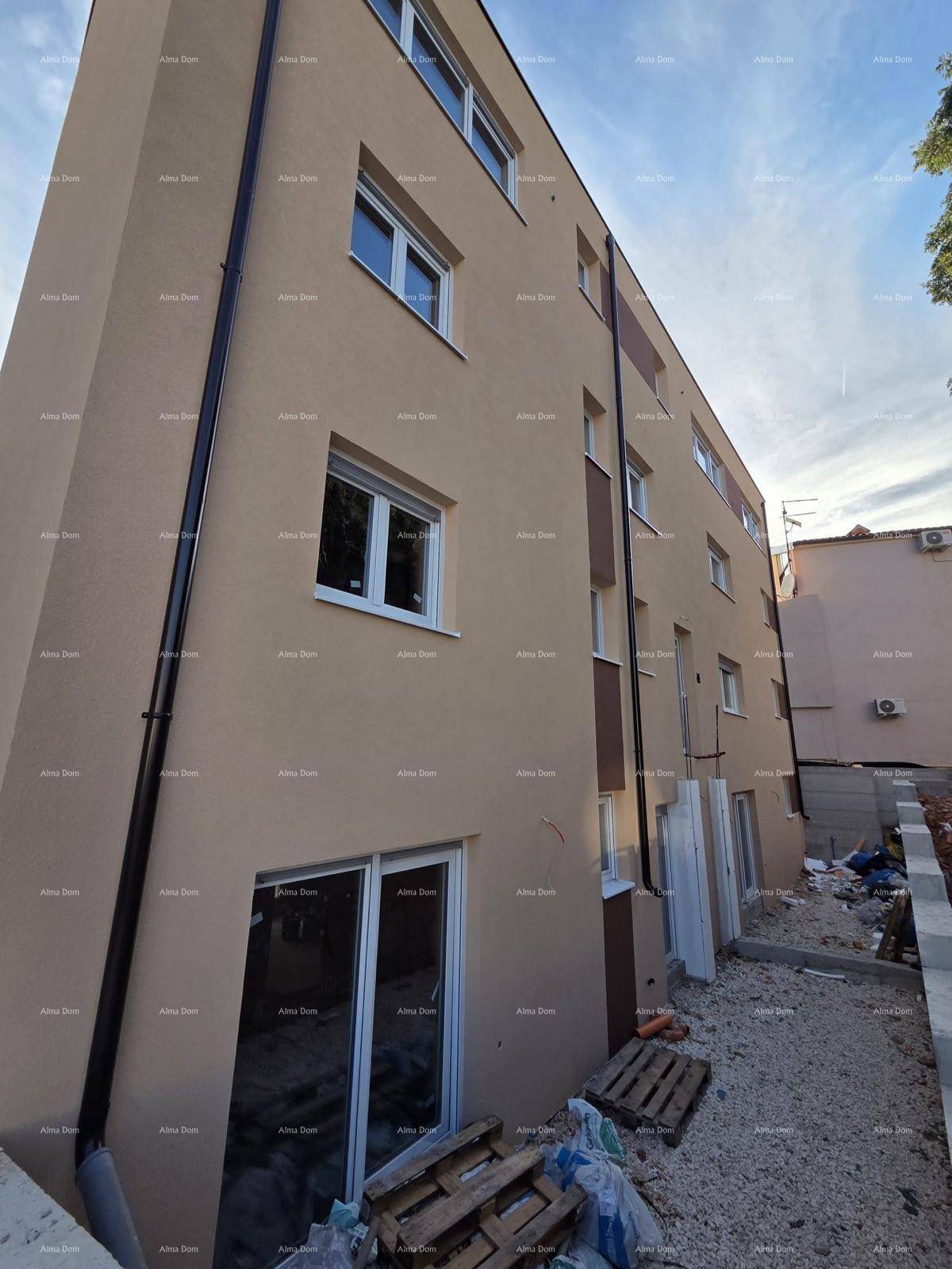 Seitenfassade des Neubaus mit Fenstern und Regenfallrohren, umgeben von Baustellenmaterial.