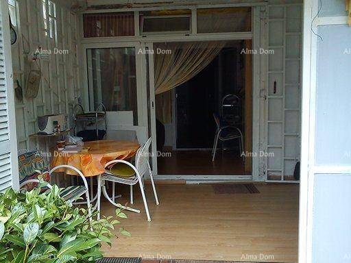 Überdachte Loggia mit Holzboden und Esstisch, die zum Innenbereich des Hauses führt.