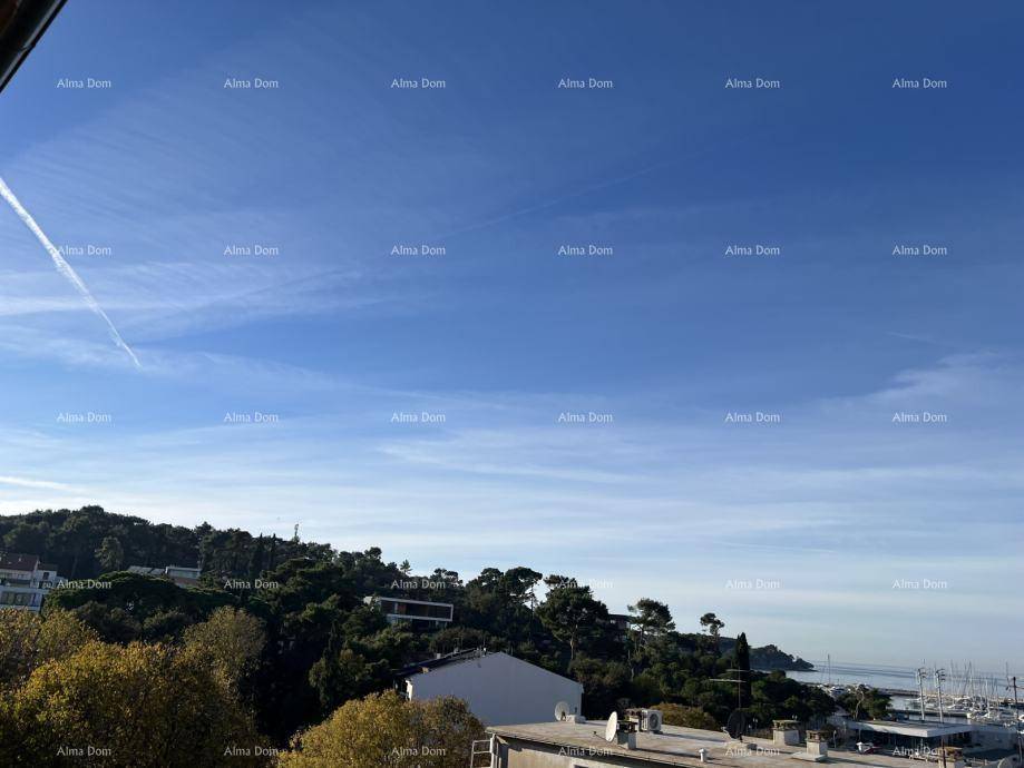 Panoramablick über grüne Hügel, Dächer und das weite Meer unter einem klaren blauen Himmel.
