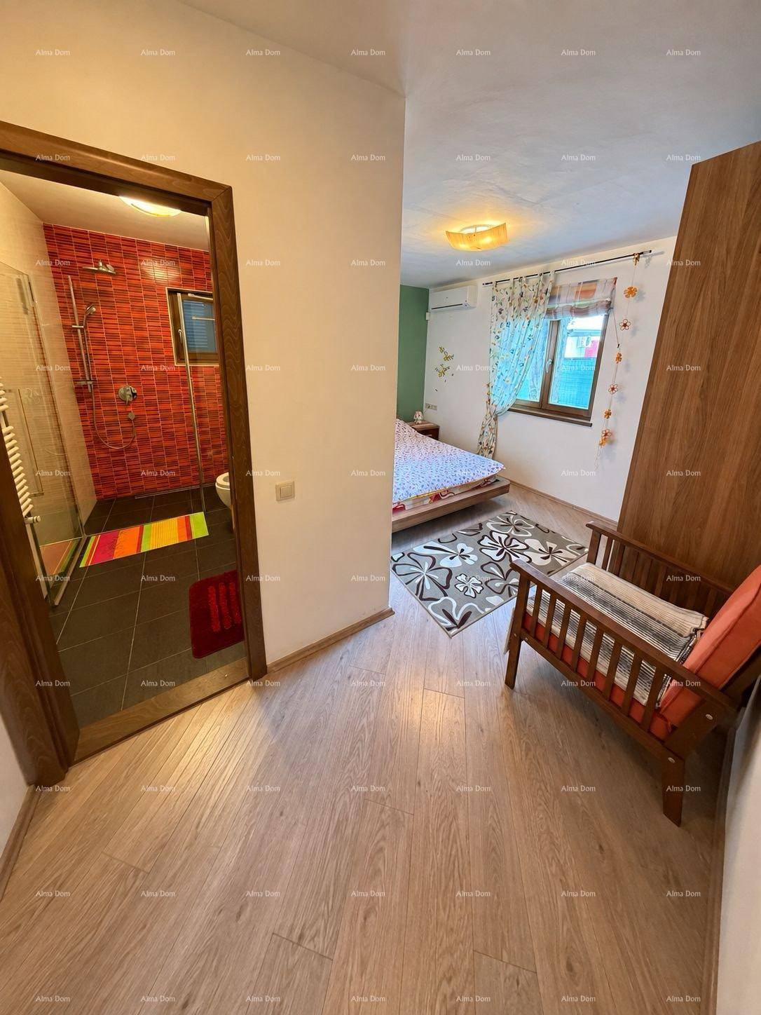 Blick auf ein Schlafzimmer mit Holzboden und ein angrenzendes Badezimmer mit roter Duschwand.