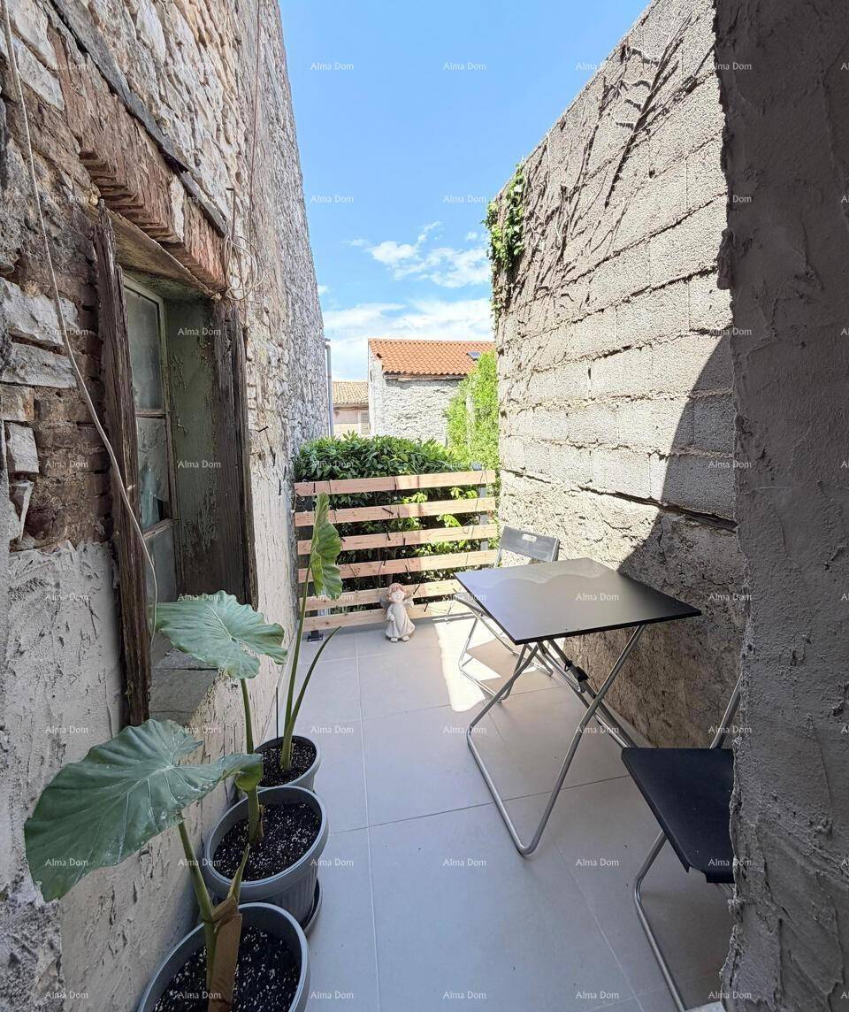 Gemütliche kleine Terrasse zwischen Steinmauern mit Sitzgelegenheit und Topfpflanzen.