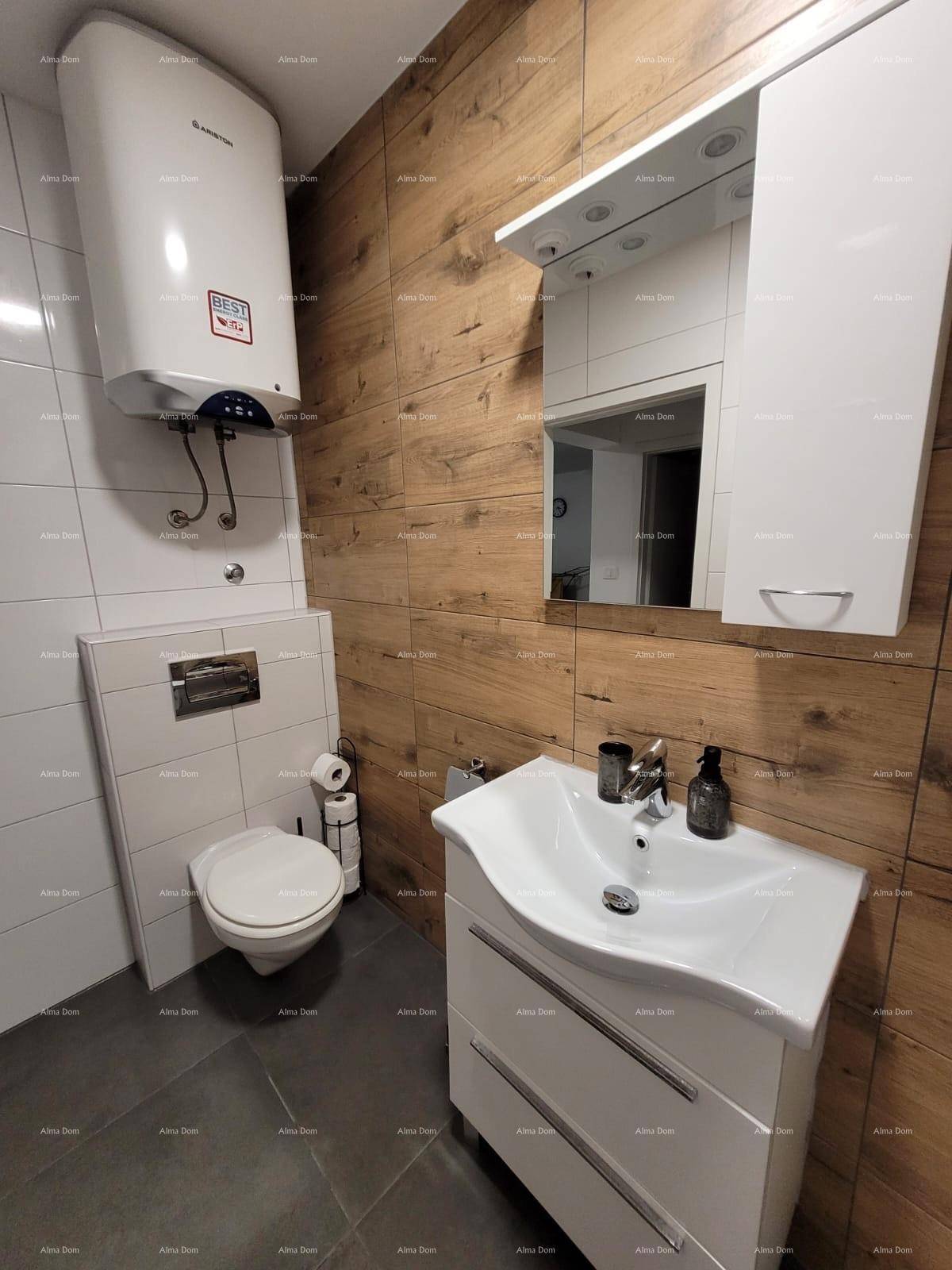 Funktionelles Badezimmer mit wandhängendem WC, Waschtisch und Warmwasserboiler.