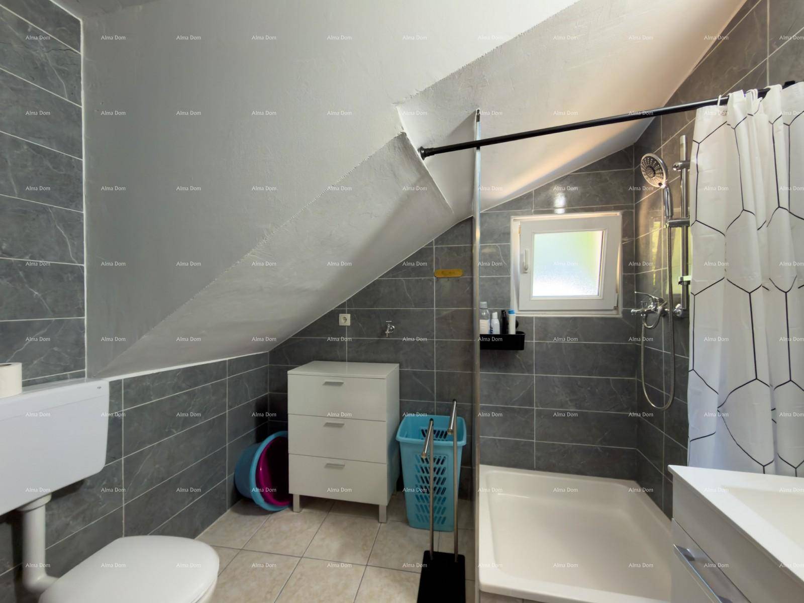 Badezimmer mit WC, Duschbereich und modernen grauen Fliesen.