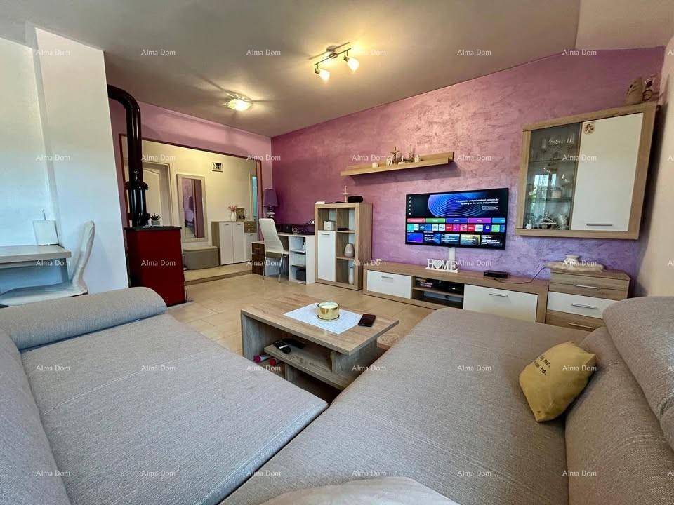 Wohnzimmer mit Kaminofen, Fernseher und moderner Einrichtung in warmen Farbtönen.