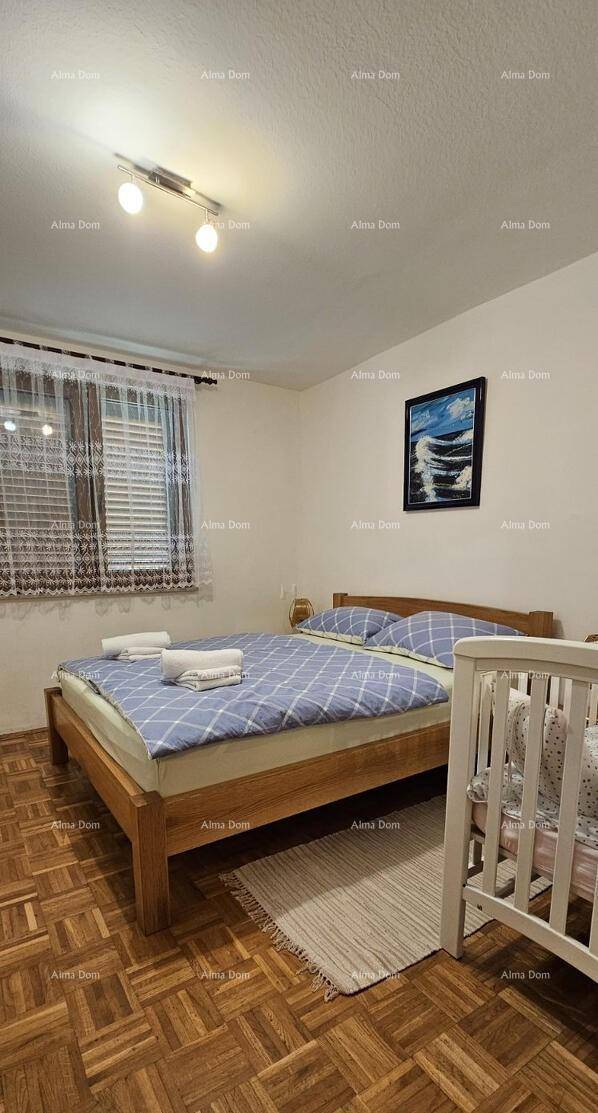 Schlafzimmer mit Doppelbett, Holzboden und einem Babybett.