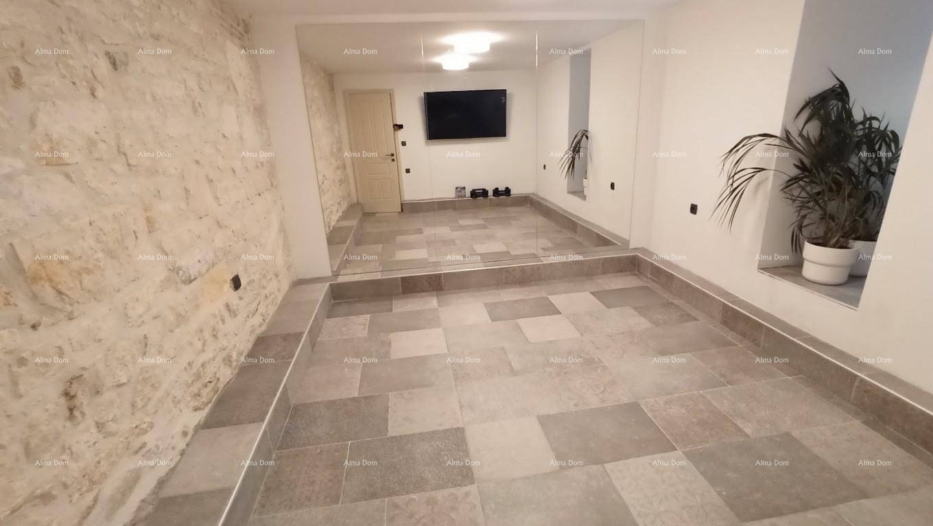Geräumiger Raum mit Fliesenboden, Steinwand und Wandfernseher, bereit zur Einrichtung.