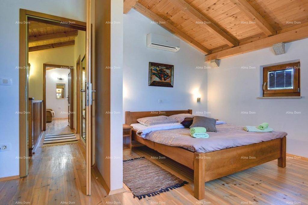 Schlafzimmer mit Holzbalkendecke, Holzboden und Klimaanlage, mit Blick in den Flur.