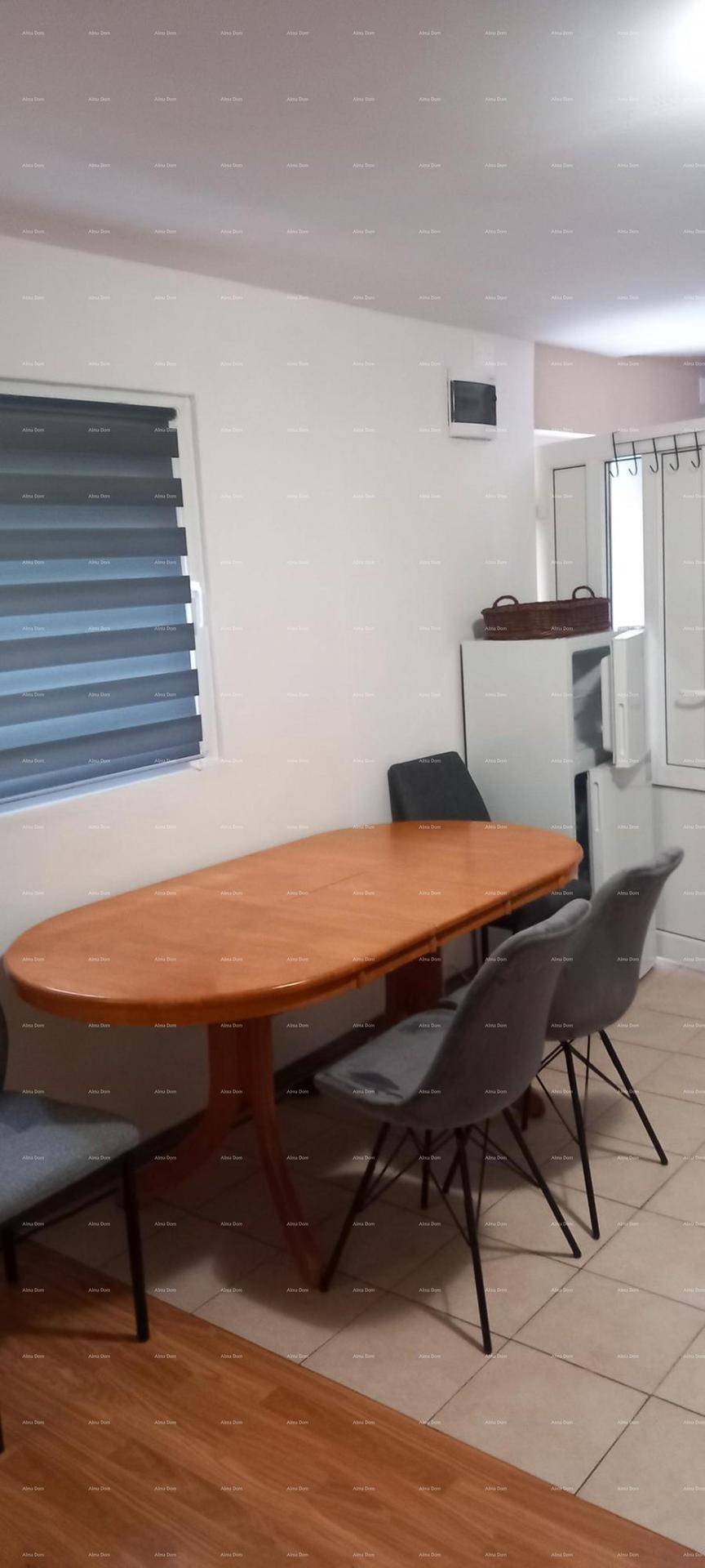 Essbereich mit Holztisch und Stühlen, angrenzend an den Küchenbereich mit Kühlschrank.