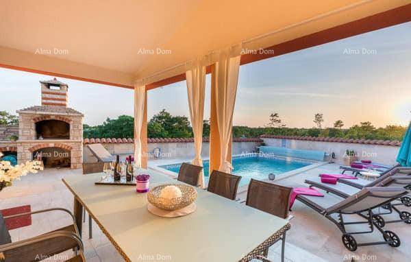 Überdachte Terrasse mit Esstisch, Liegestühlen und Blick auf den Pool und den Außenkamin.