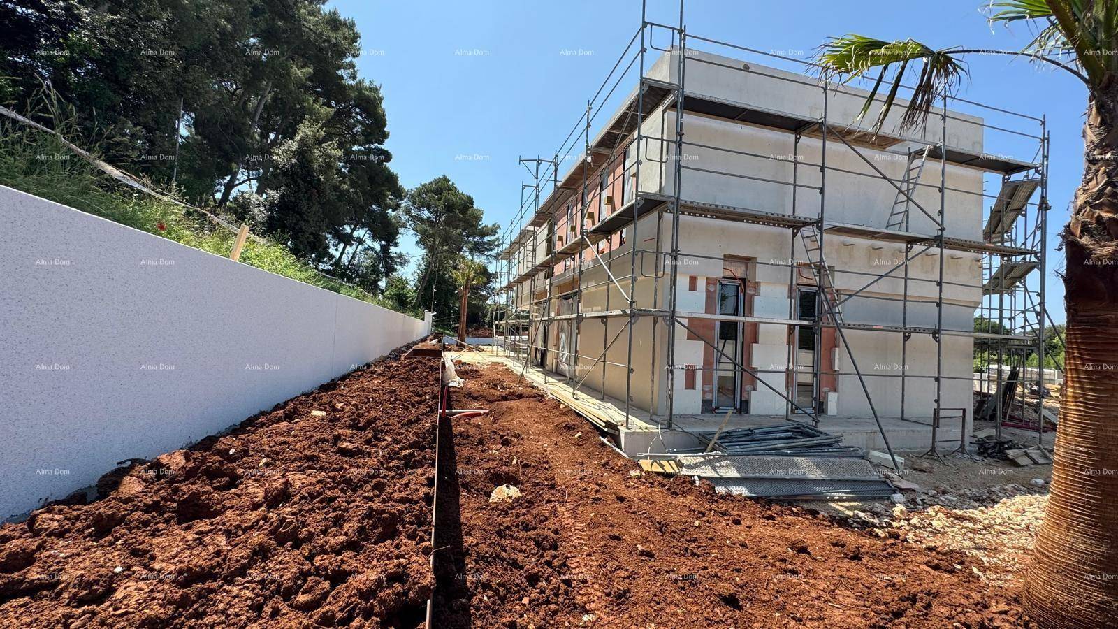 Baustelle eines modernen Hauses mit Gerüst und beginnender Fassadenverkleidung unter blauem Himmel.