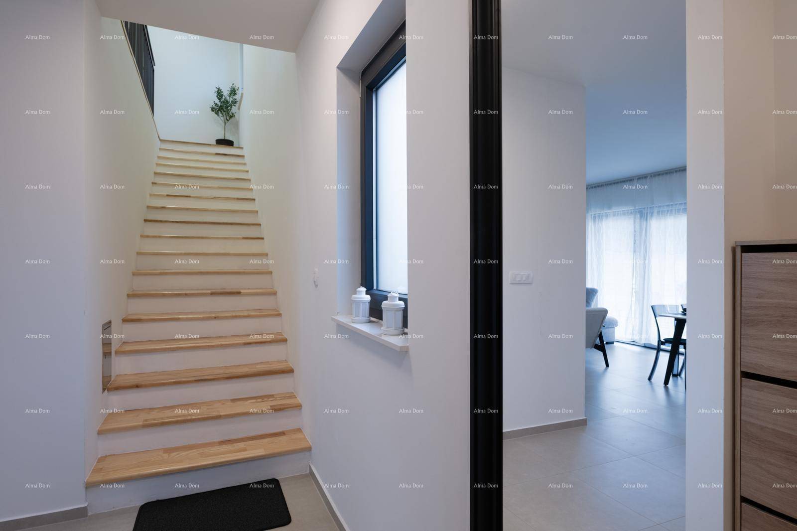 Heller Flur mit Holztreppe und modernem Design, der zu den oberen Etagen führt.