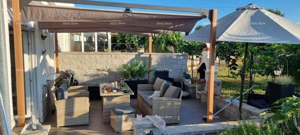 Einladende Terrasse mit bequemen Rattanmöbeln unter einer schattenspendenden Pergola und großem Sonnenschirm.