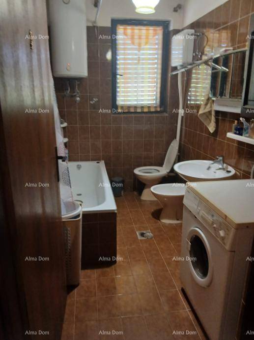 Badezimmer mit Badewanne, Toilette, Bidet und Waschmaschine, gefliest in Brauntönen.