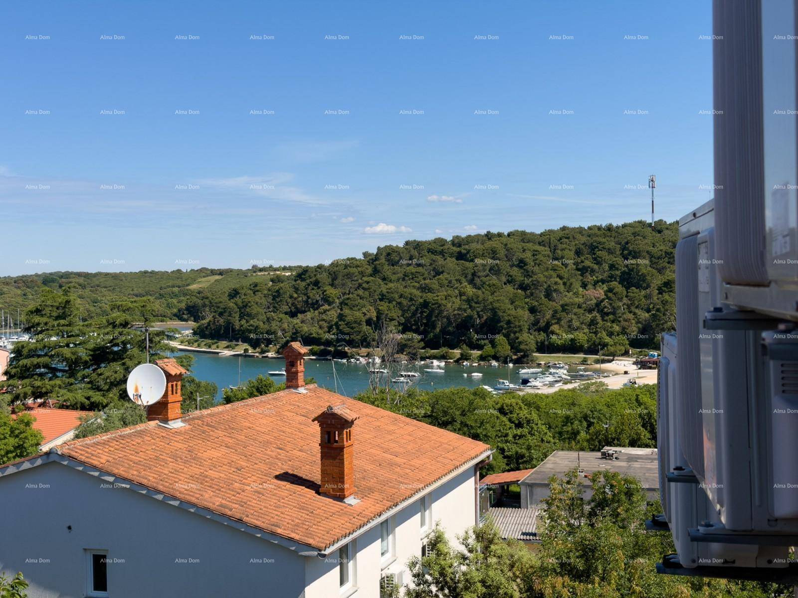 Panoramablick auf eine Bucht mit Booten, umgeben von grünen Hügeln und einem Haus mit Ziegeldach.
