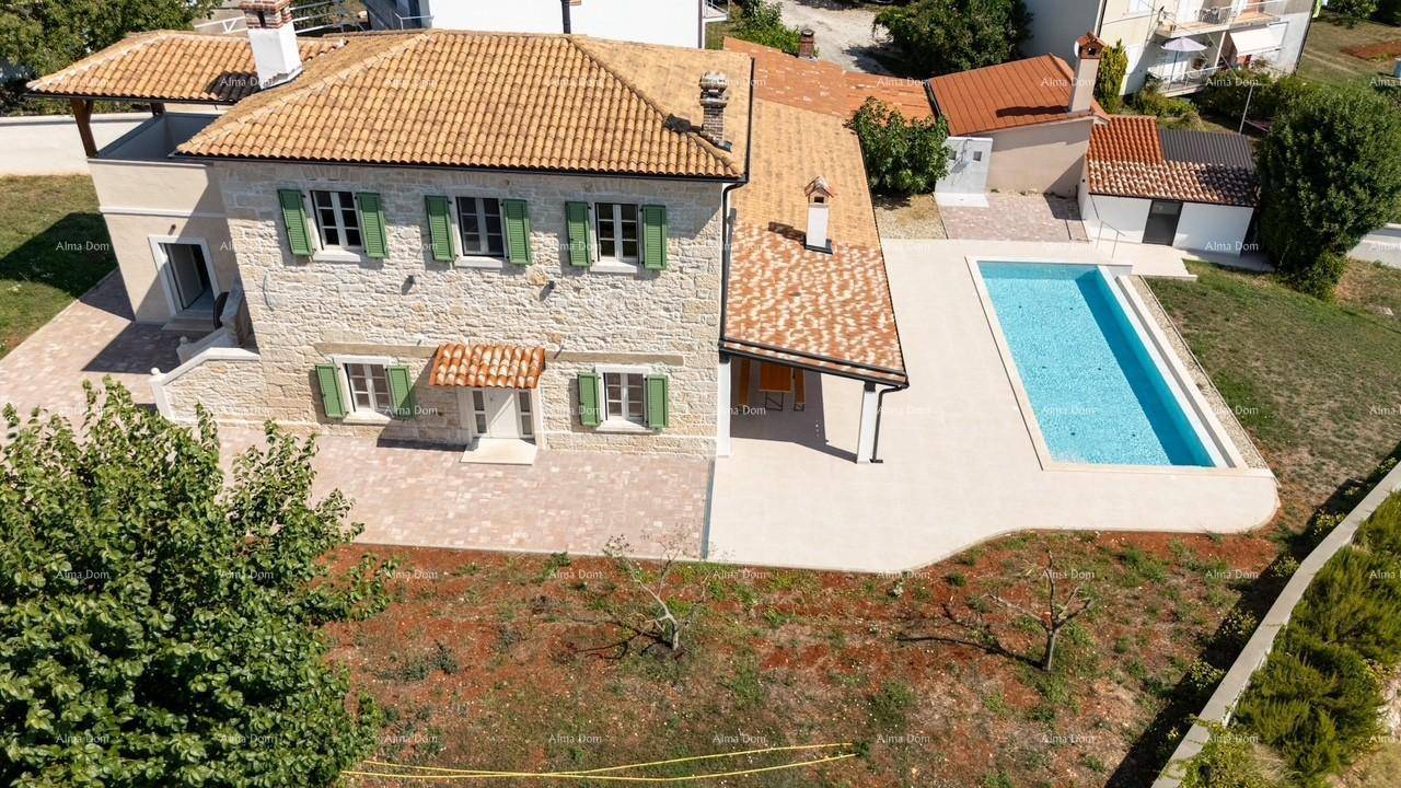 Luftaufnahme eines traditionellen Steinhauses mit Terrakottadach, grünen Fensterläden und einem Swimmingpool.