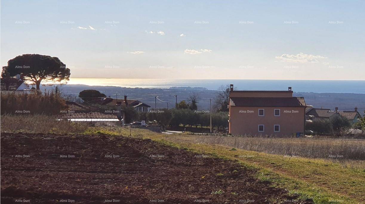Panoramablick über Felder und Häuser mit dem Meer am Horizont bei Sonnenuntergang.