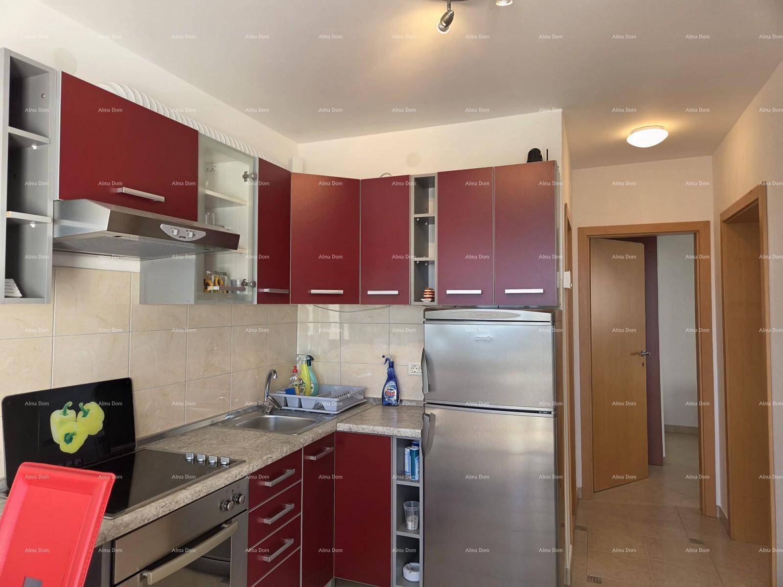 Küche mit roten Schränken, Herd, Kühlschrank und Fliesenboden.